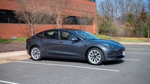 A Tesla Model 3 from the side in a parking lot. 