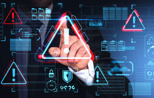 Hand of businessman using malware alert cybersecurity interface with triangular warning icon on touch screen over blue background.