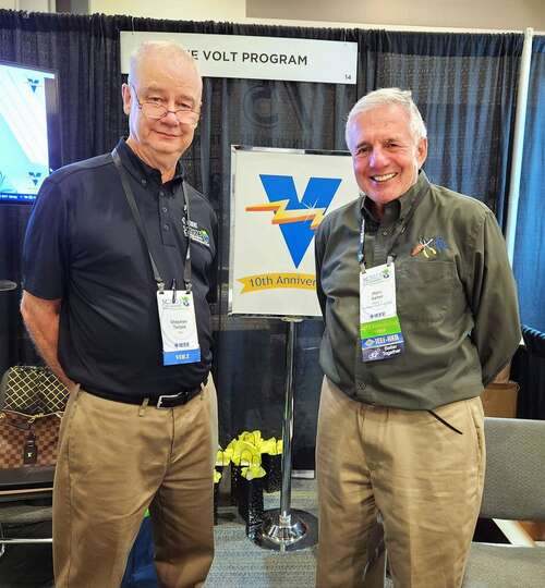 two men standing for a portrait in a conference setting