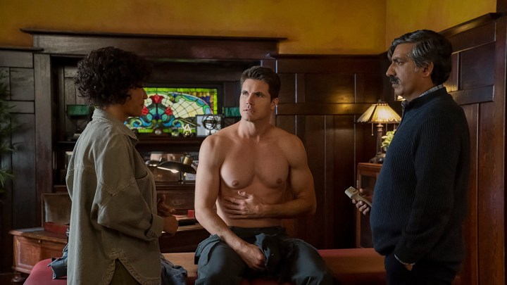 Nathan sitting without a shirt and holding his stomach while Nora and Dr. Kapoor look on in Upload.