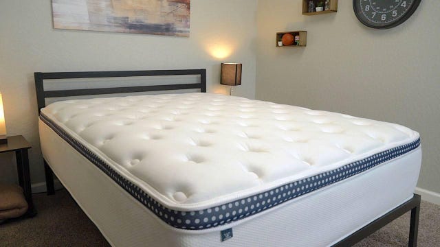 The WinkBed mattress on top of a metal bed frame in a bright room