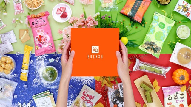 The Bokksu subscription box and a lot of snacks are displayed against a colorful background.