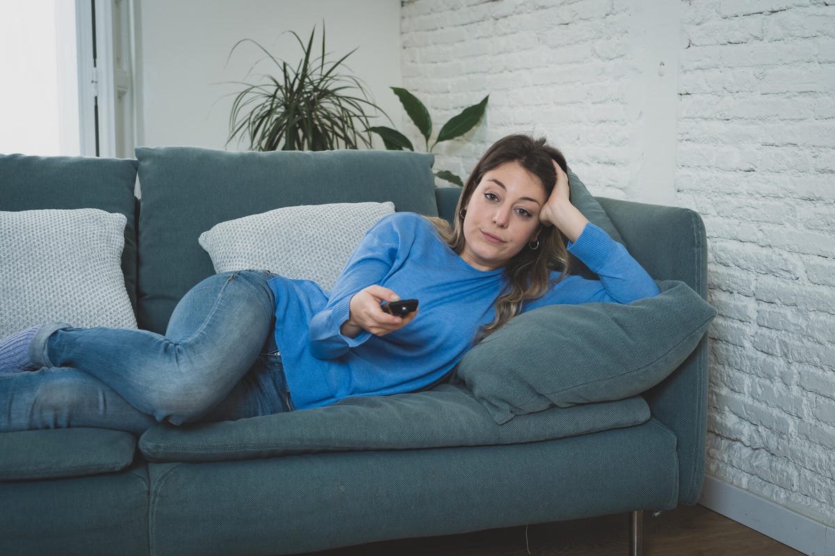 Bored woman watching TV on couch