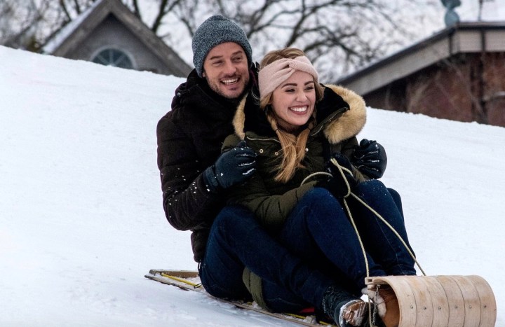 A man and woman go down a sled on a hill.