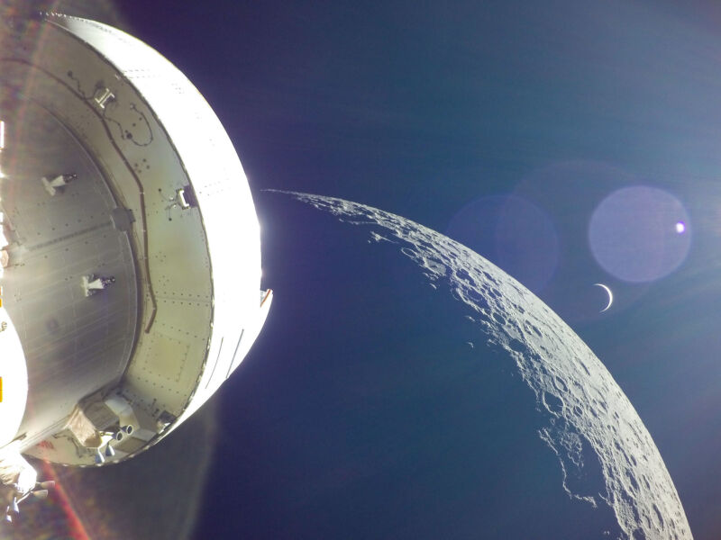 A crescent Earth rises over the horizon of the Moon in this view from NASA's Orion spacecraft on the unpiloted Artemis I test flight in December 2022.