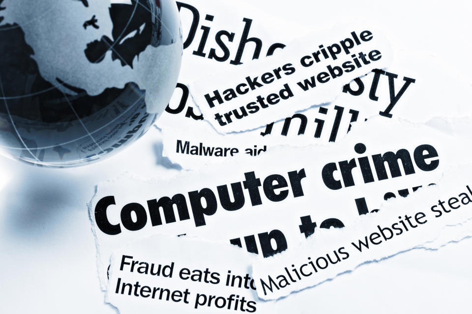 A blue glass globe-shaped paperweight rests on print headlines covering  aspects of Internet and computer-related crime.