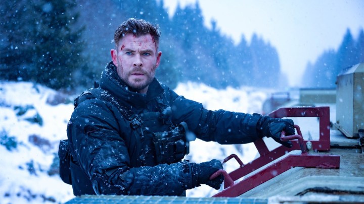 Chris Hemsworth as Tyler Rake looking to the distance while riding a snow vehicle in Extraction 2.