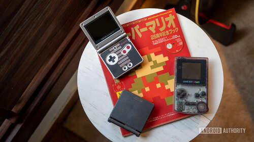 GameBoy Advance with other consoles placed on a Mario magazine