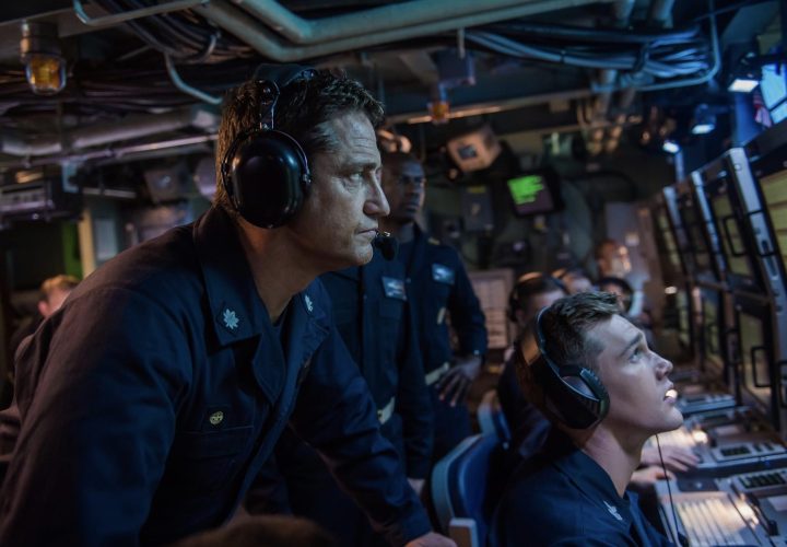 A submarine commander listens to sound on a headphones.