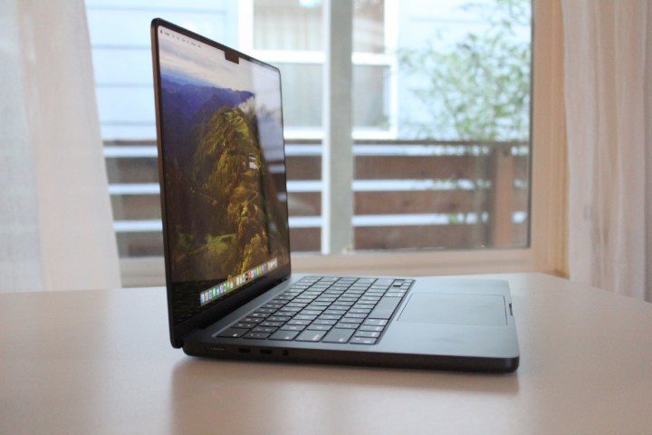 A MacBook Pro on a table in front of a window.