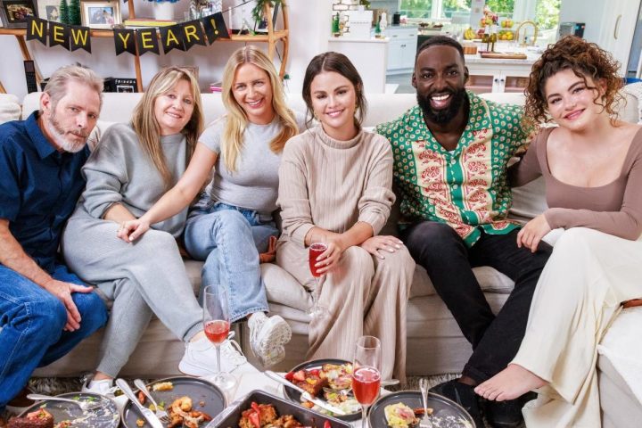 Selena Gomez sits on a couch next to friends and family.