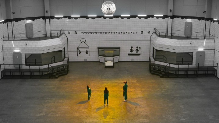 Three people stand in an empty room in Squid Game: The Challenge.