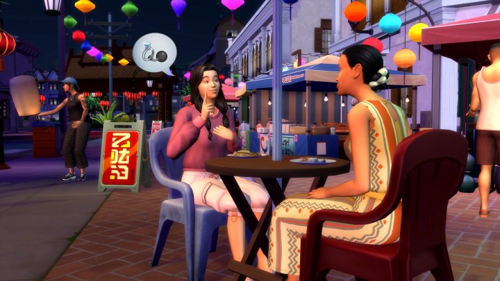 Two Sims sit at an outdoor cafe table at night, chatting.