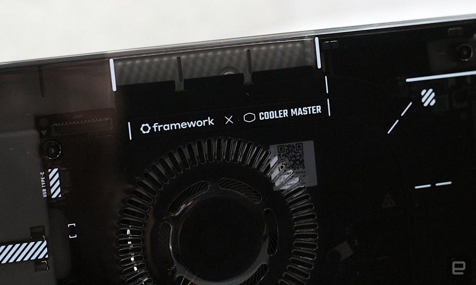 Close up of the Framework x Cooler Master logo on the front of the case in front of a grey painted wall.