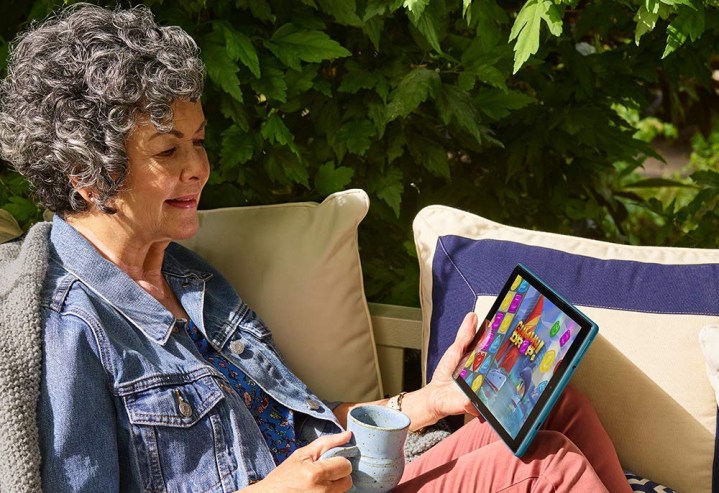 A woman watches content on an Amazon Fire HD 10 tablet.