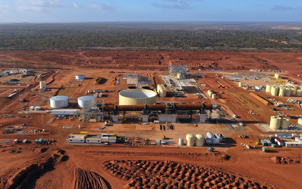 An aerial photo of a red-brown dirt landscape with buildings, tanks, equipment and vehicles