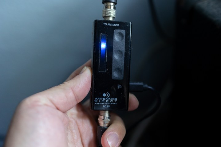 An over-the-air antenna amplifier held in a hand.