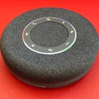 A Beyerdynamic speakerphone against a solid red background.