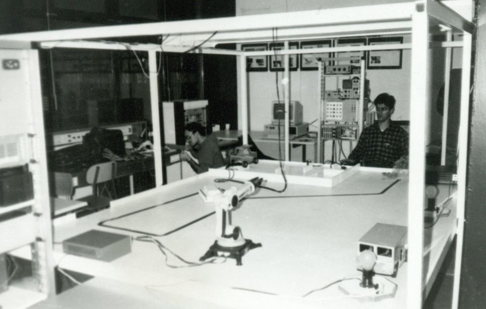 Black and white photo of table with a race track on it with two people sitting behind it