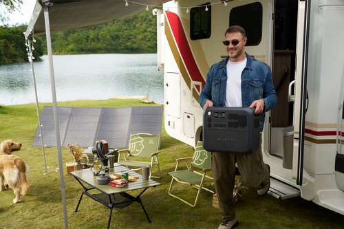 bluetti power station being held by man outside caravan