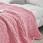 Pink blanket thrown over a white bed