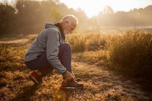 Man lacing up workout shoes outside.