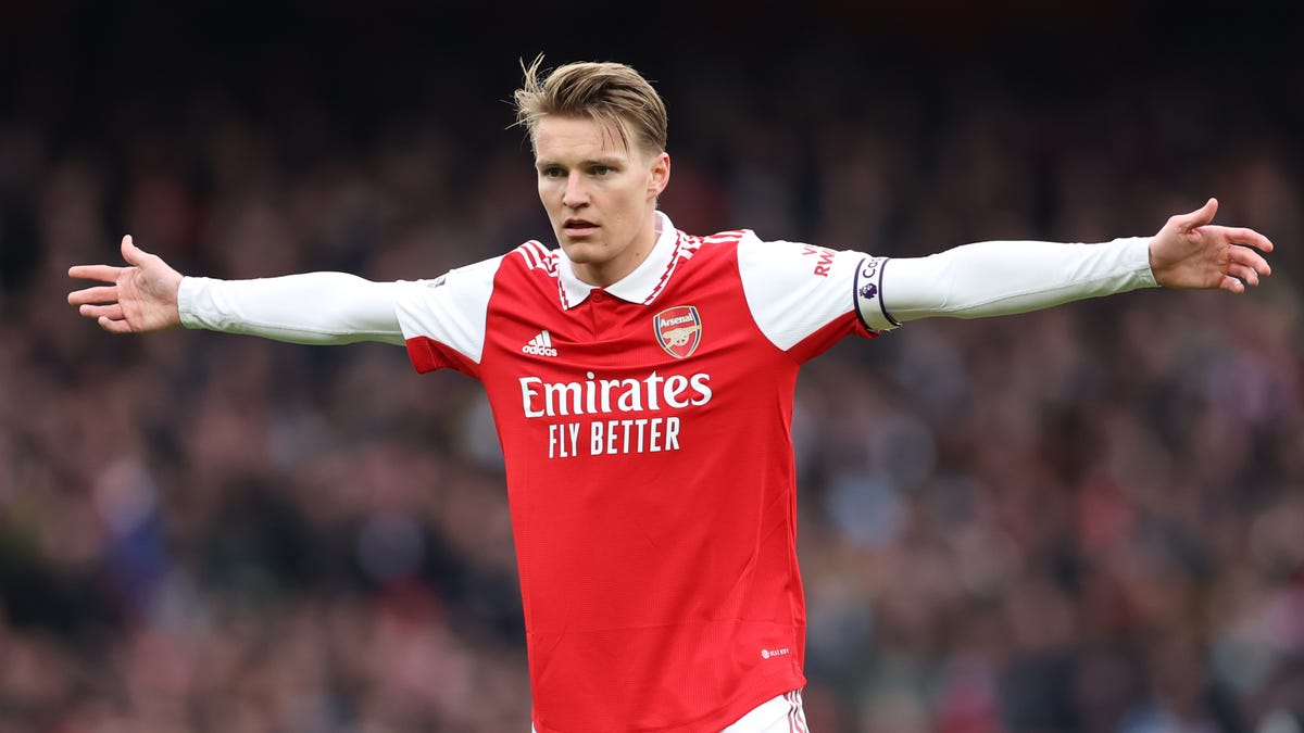 Arsenal midfielder Martin Odegaard standing with both arms outstretched.