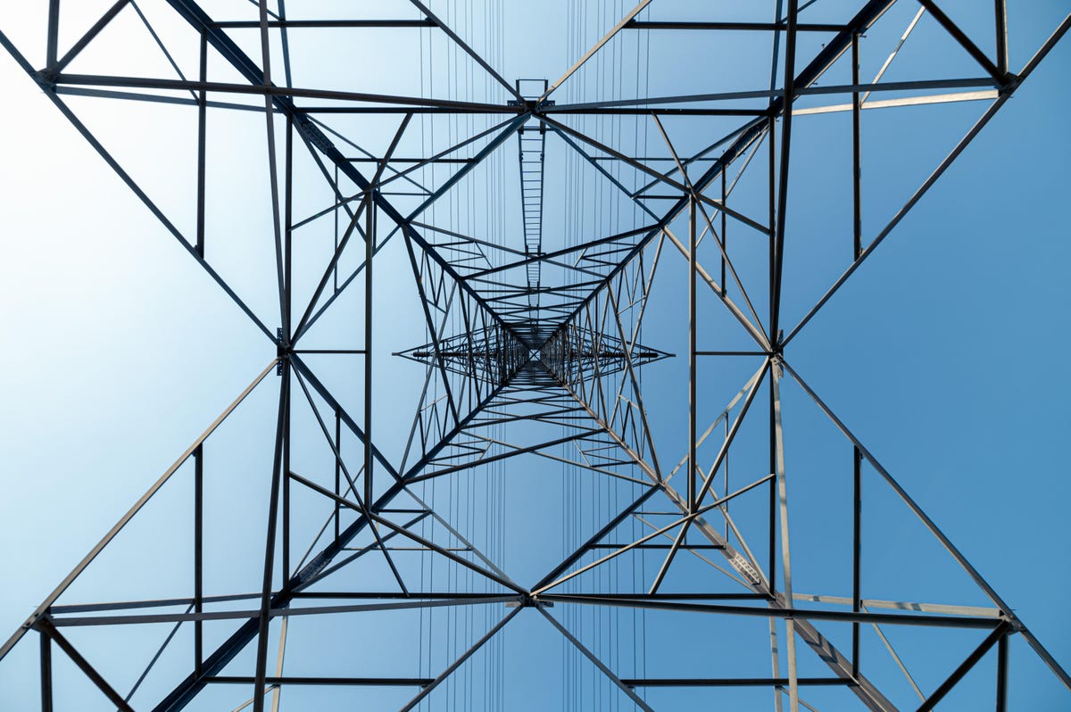 Looking up through a steel tower holding power lines.