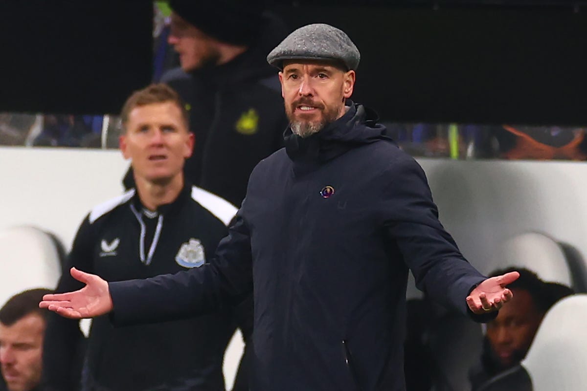 Erik Ten Hag in a flat cap and gray jacket, gesturing with hands outstretched