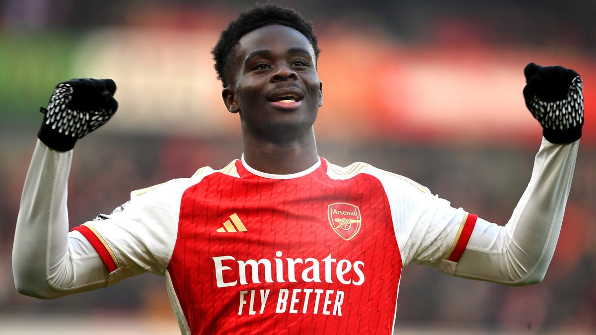 Arsenal forward Bukayo Saka celebrating with both fist raised.