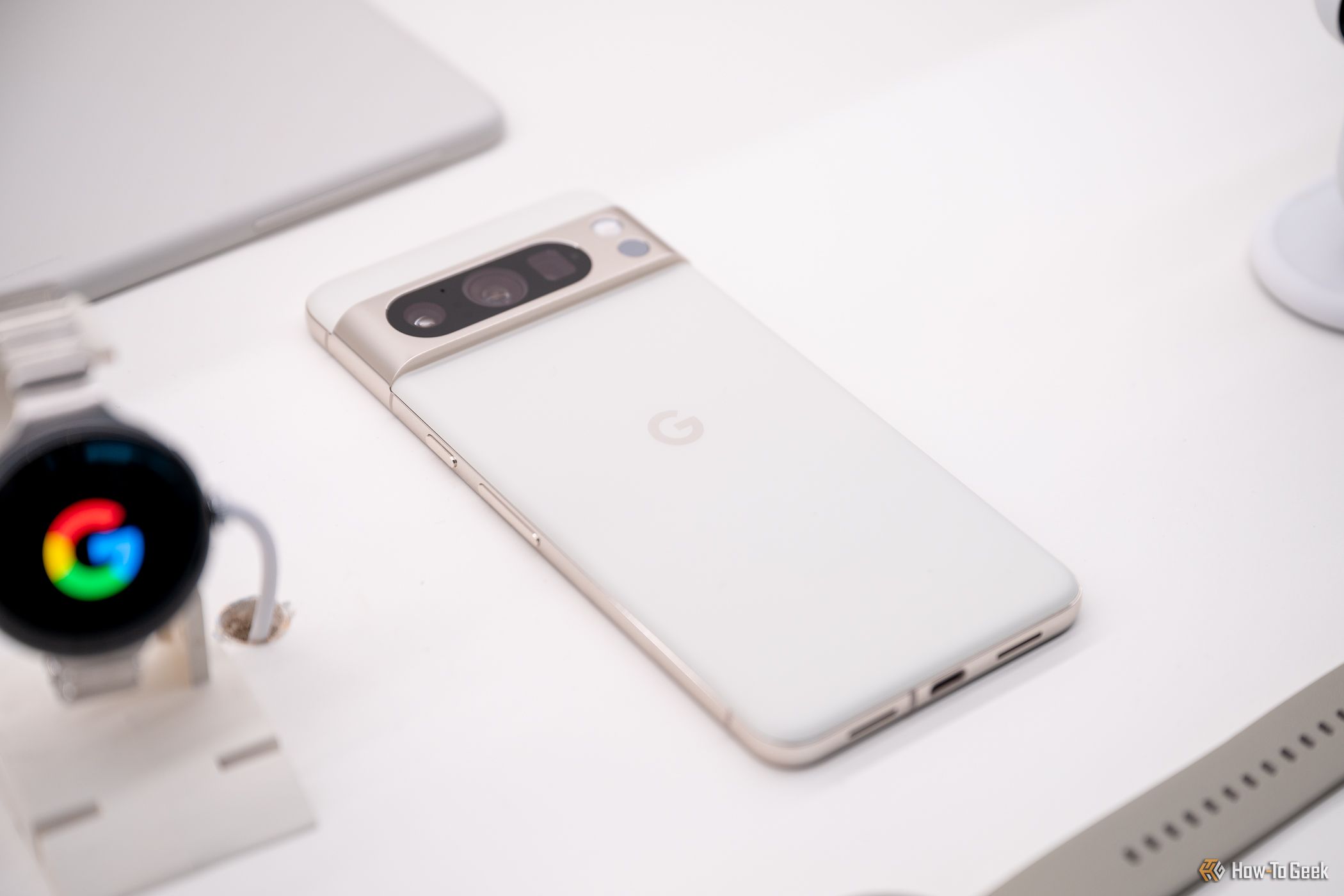 Google Pixel 8 Pro laying on a table next to a Google Pixel Watch 2