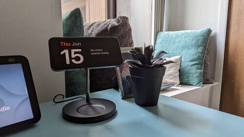 Photo of an iPhone on a charging dock, on top of a blue nightstand.