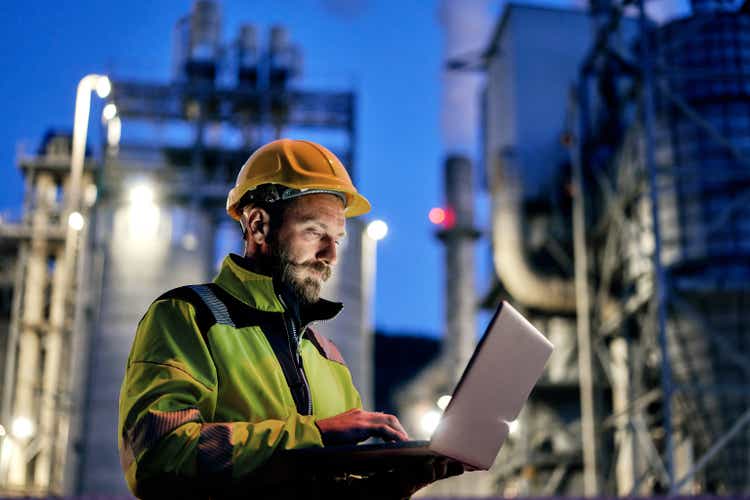 Male engineer using laptop during night shift.