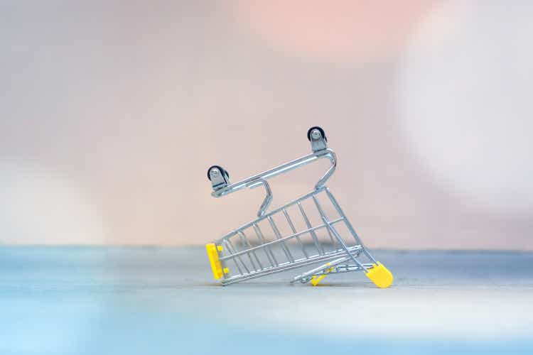 Empty supermarket shopping cart upside down on a ground