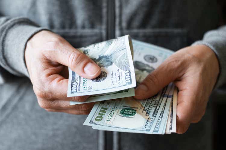 White female model shows dollar bills in her hand closeup front view