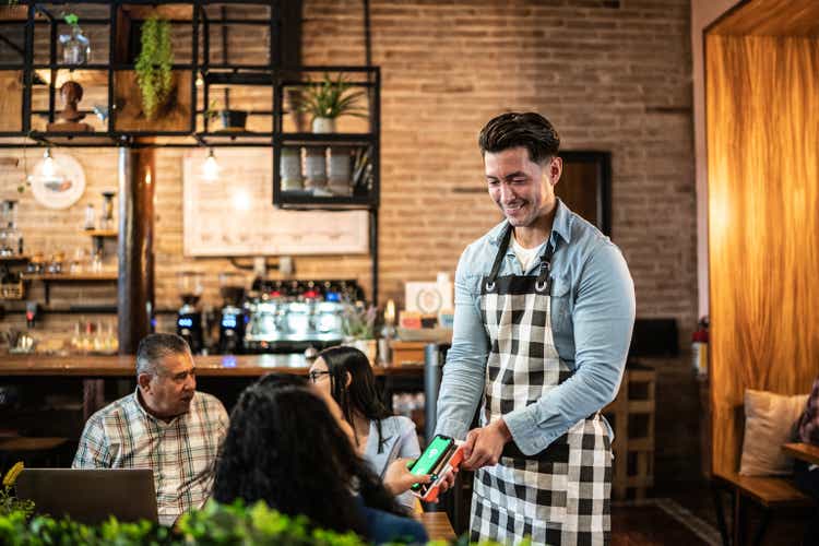 Waiter receiving payment by phone at a restaurant