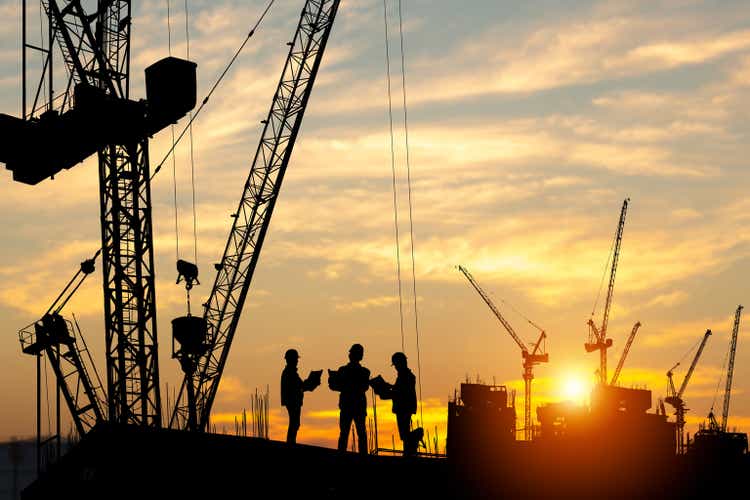 Silhouette of Engineer and worker team on building site, construction site at sunset in evening time