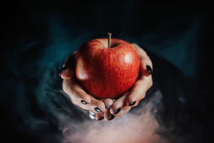 Woman as witch offers red apple - symbol of toxic proposal, lure.