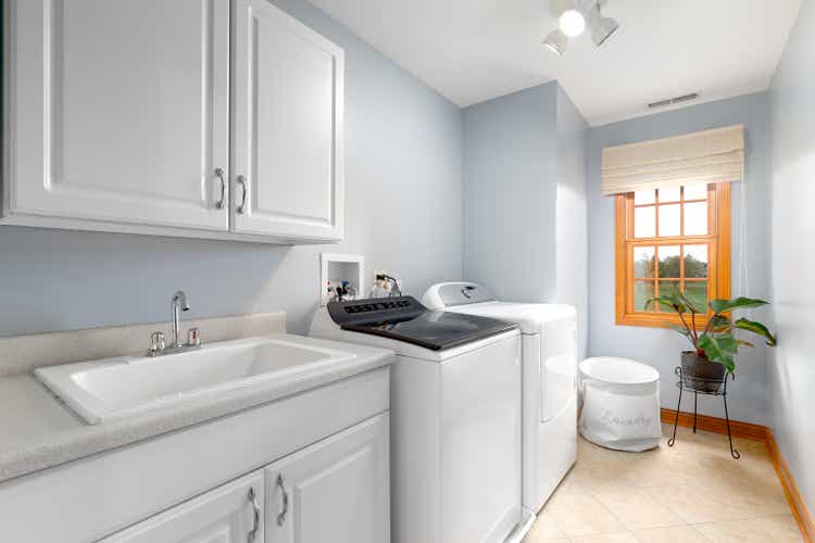 A laundry room with white cabinets and appliances.