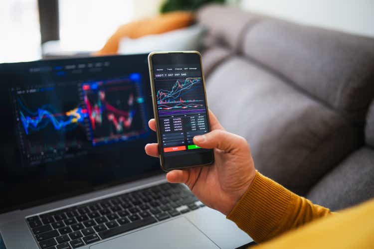 Man buying cryptocurrency at home via laptop and phone.