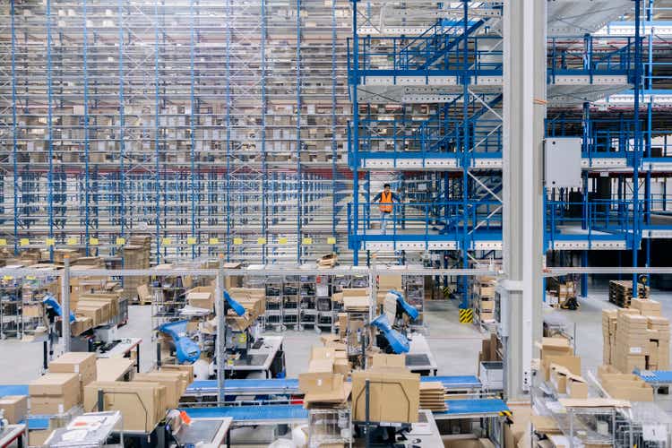 Interior of a large distribution warehouse company with worker standing in balcony