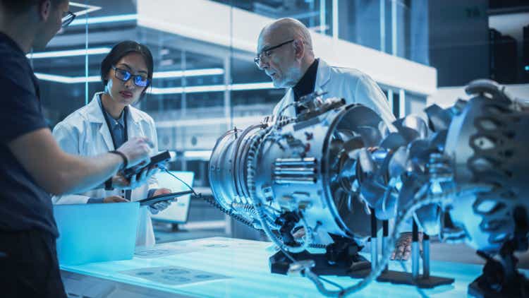 Team of Multicultural Engineers Use Testing Device and Tablet Computers, Analyze and Discuss How a Modern Electric Turbine Motor Works. High Tech Research Laboratory with Modern Equipment.