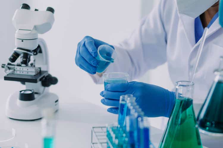 Medical Development Laboratory: Caucasian Female Scientist Looking Under Microscope, Analyzes Petri Dish Sample. Specialists Working on Medicine, Biotechnology Research in Advanced Pharma Lab