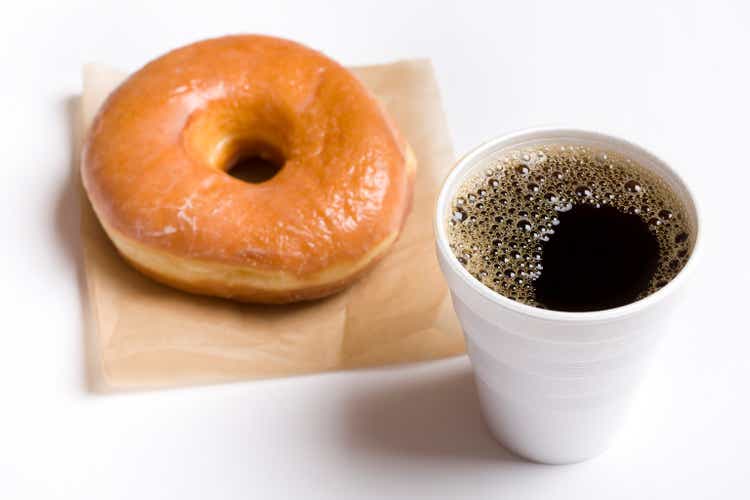 Close-up of a cup of black coffee and a glazed donut