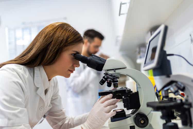 Doctor looking thru microscope while doing research in his lab