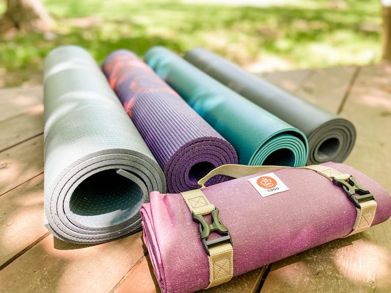 four yoga mats rolled up outside on a deck