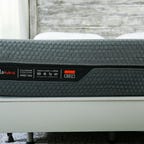 layla hybrid mattress on top of an adjustable bed frame with a wooden headboard in the back.