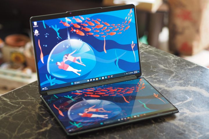 The two screens of the Yoga Book 9i open on a table.