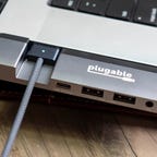 Plugable 5-in-1 USB C Hub with MagSafe support connected to a 16-inch MacBook Pro's USB-C ports on the left side of the laptop.