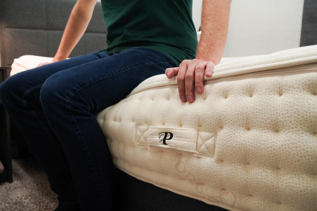 Person sitting on the edge of the PlushBeds Botanical Bliss mattress to test its edge support